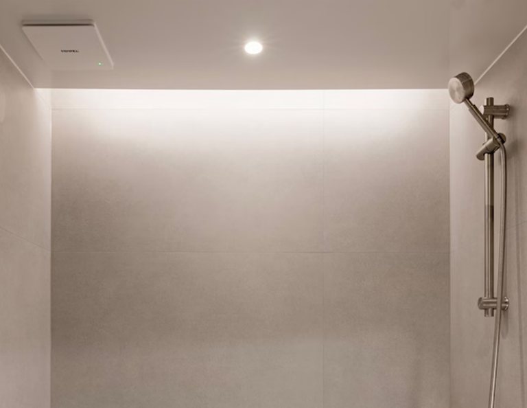 Buồng tắm xám có dải hắt sáng T5 chạy sát trần và quạt đèn âm trần